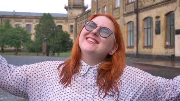 Dik gember meisje met bril is wandelen in het park onder regen, verhogen handen, enthousiast over regen, inspiratie concept — Stockvideo