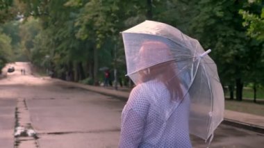 Şişko kız Kızıl silüeti Park yağmur altında yolda yürüyor, dönüm, gülümseyen, şemsiye tutan, arkadan görünüm