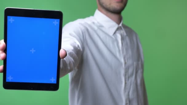 Hombre joven con barba en camisa blanca apuntando tableta con cromakey en la cámara, fondo cromakey — Vídeo de stock