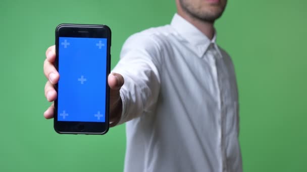 Young man in white shirt showing phone with chromakey at camera, chromakey background — Stock Video