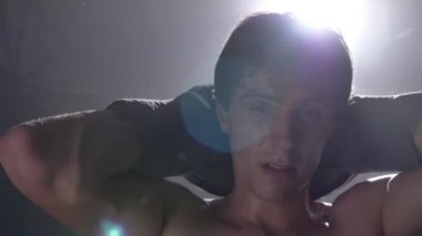 Ellerini kaldırma ve kamera, arka planda parlak aydınlatma bakarak yorgun üstsüz boxer