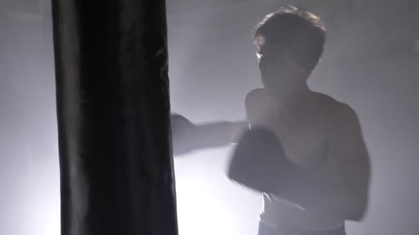 Топлес кикбоксер в перчатках боксерская боксерская боксерская груша, тренировка для чемпиона в темной комнате с туманом — стоковое видео