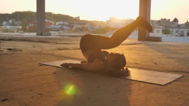 Niña yogui está de pie en la pose de arado en el edificio abandonado en verano al atardecer, estilo de vida saludable, concepto de movimiento, concepto de deporte — Vídeos de Stock