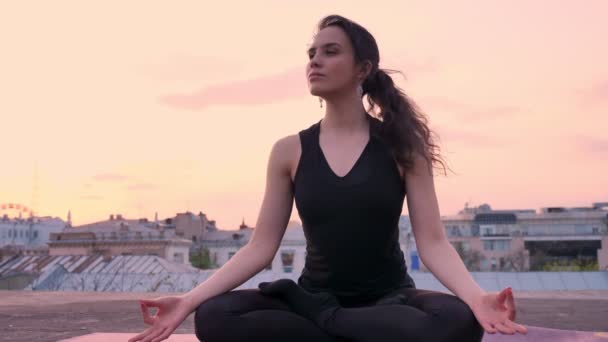 Niña yogui está sentado en la pose de loto en la azotea en verano al atardecer, estilo de vida saludable, concepto de movimiento, concepto de meditación — Vídeo de stock