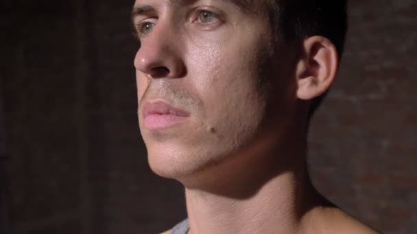 Portret van zelfverzekerde Kaukasische jonge man kijken ernaar uit, permanent in bakstenen gebouw — Stockvideo