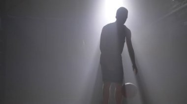 Top sürme ve ışıldak arka planda Karanlık sisli odada oynamaktan topu atma basketbolcu