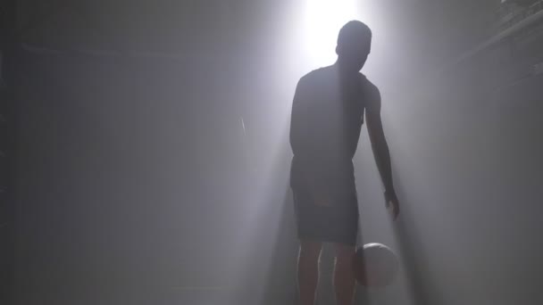 Joueur de basket dribble et lancer la balle, jouer dans la chambre sombre brumeuse avec projecteur en arrière-plan — Video