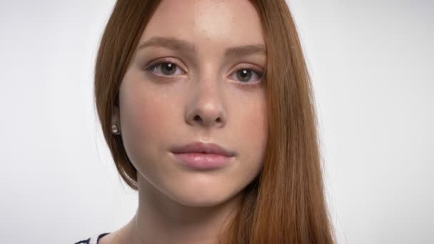 Обличчя молодої спокійної дівчини-імбируси дивиться на камеру, білий фон — стокове відео