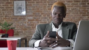 Telefona yazma ve başarılı patron modern ofisinde oturan genç emin Afrika sarışın işadamı