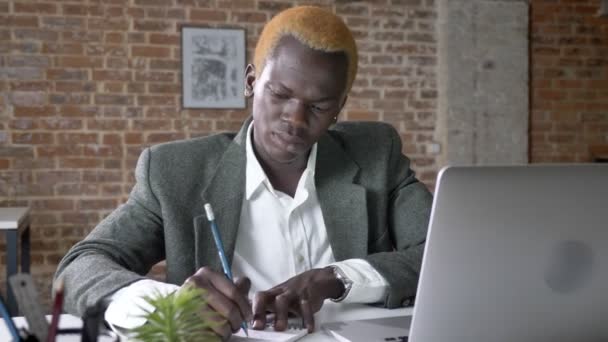 Joven empresario afroamericano confiado escribiendo notas y escribiendo en el ordenador portátil en la oficina moderna, trabajador ocupado — Vídeos de Stock