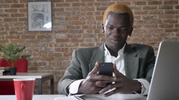 年轻自信的非洲金发商人打字在电话和坐在现代办公室, 成功的老板 — 图库视频影像