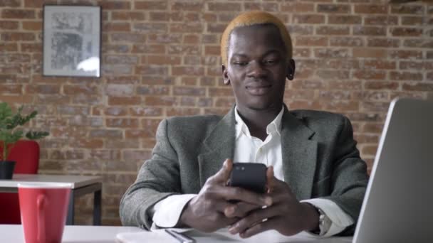 年轻的非洲裔美国金发商人在电话上发短信, 坐在现代办公室, 自信和成功的工人 — 图库视频影像