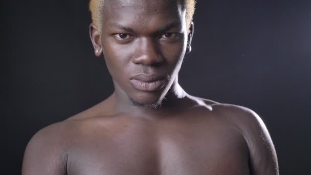 Vážně blond afroamerické nahý mladík při pohledu na fotoaparát, izolované na černé studio pozadí, jistý kulturista — Stock video