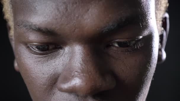 Close footage of dark-skinned blond mans eyes looking at camera, isolated on black background — Stock Video