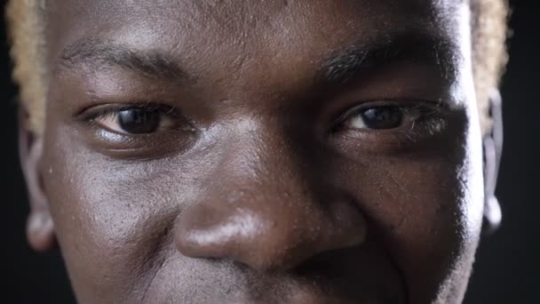 Close shot of happy african american mans eyes looking at camera, black background in studio — Stock Video