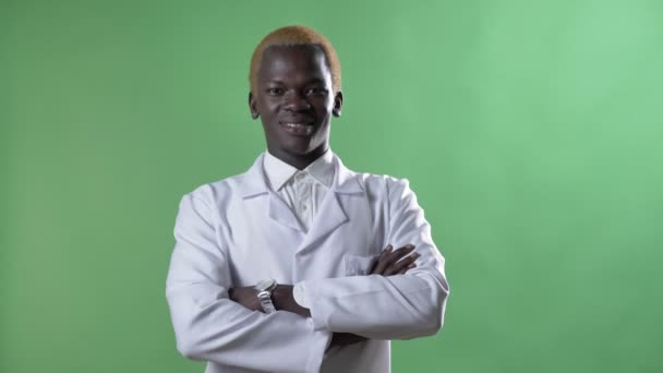Młody Afryki blond lekarz w biały płaszcz i okulary, patrząc na kamery, osamotniony na tle chromakey, pewny siebie i sukces — Wideo stockowe