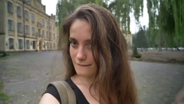 Jonge charmante vrouw met lang haar blog filmen en lachend op camera, permanent in park in de buurt van Universiteit — Stockvideo