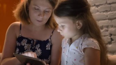 Anne evde, kanepede oturan tablet, Aile kavramı kapalı yazarak küçük kızı ile