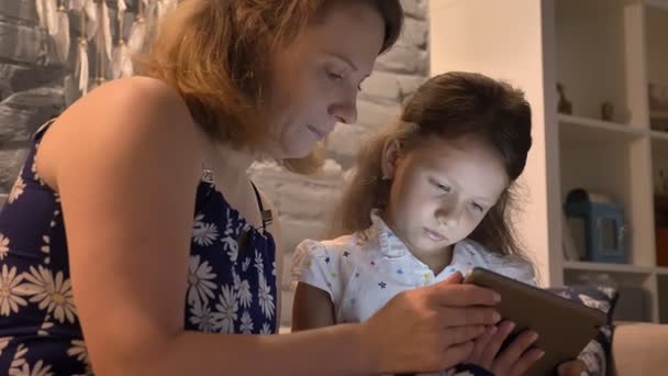 Moeder met dochtertje met behulp van tablet en zittend op de Bank bij moderne huis, familie concept met gadget, binnenshuis — Stockvideo