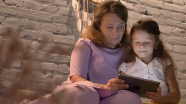 Anne ile küçük kızı tablet, çocuk gülüyor, Aile kavramı üzerinde aygıt ile kapalı oyun