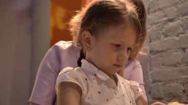 Anne küçük kızının saç örgü ve onu, modern, Aile kavramı kapalı oturma odasında öpüşme