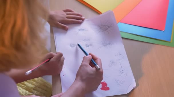 Madre y su hijo dibujando en papel o haciendo deberes de arte juntos, sentados en la mesa en casa, tiro superior — Vídeos de Stock