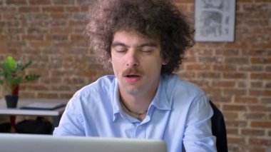 Kıvırcık saçlı stresli iş adamı iş modern ofis içinde laptop ile masada oturan ile ilgili sorunlar var
