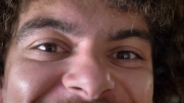 Zamknij footage szalony człowiek oczy patrząc na kamery i uśmiechnięty, kręcone włosy z woluminu — Wideo stockowe