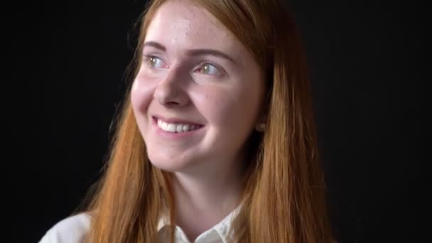 Encantadora joven feliz con el pelo de jengibre sonriendo con los dientes, aislado en el fondo del estudio negro — Vídeos de Stock