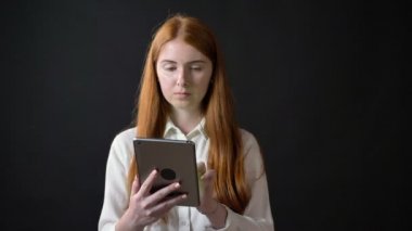 Genç kadın tablet chroma anahtar ile tutarak ve başparmak gösterilmesini, izole siyah arka plan üzerine beyaz gömlekli zencefil