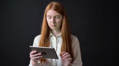 Zencefil genç kadın gösterilen chromakey tabletiyle kadar başparmak ve başını sallayarak, gülümseyen, siyah arka plan üzerine izole