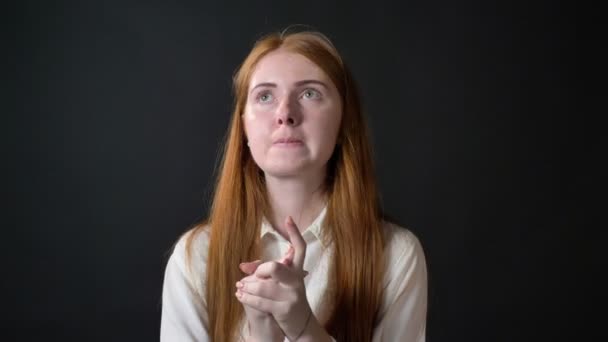 Mujer de jengibre joven reflexiva en camisa blanca decidiendo y preocupante, aislado sobre fondo negro — Vídeos de Stock