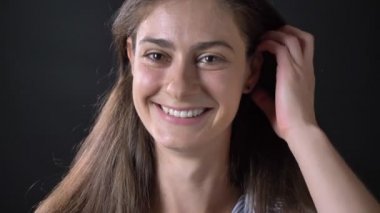 İle gülümseyen ve saçları siyah arka plan üzerine izole, dokunmadan güzel genç kadın portresi