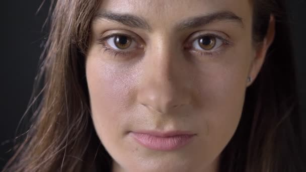 Close portrait of young serious beautiful woman looking at camera, isolated on black background — Stock Video