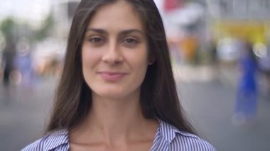 Kamera, kentsel sokakta, gündüz ayakta bakarak ve ile gülümseyen sevimli genç kadın