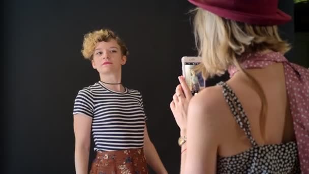Ung charmig modell med lockigt hår poserar för foto när vän att ta bilder av henne, isolerad på svart bakgrund — Stockvideo