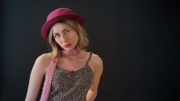 Young blonde woman in pink hat posing for photo, standing isolated on black studio background — Stock Video