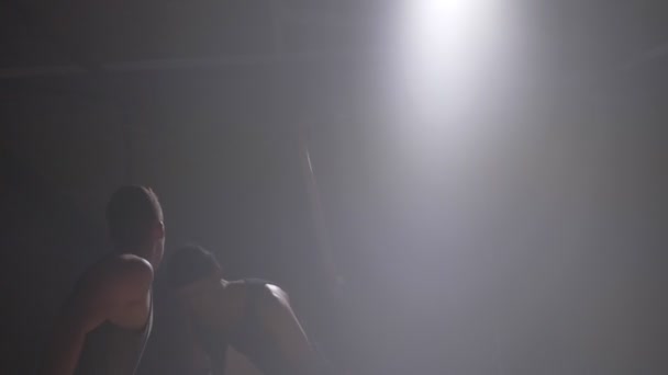Dos jugadores de baloncesto en la sombra jugando uno a uno en el interior de la habitación con humo y alumbrado — Vídeos de Stock