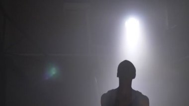 Bir basketbol oyuncusu siluet ışıldak ile karanlık sisli odada top oynamaktan