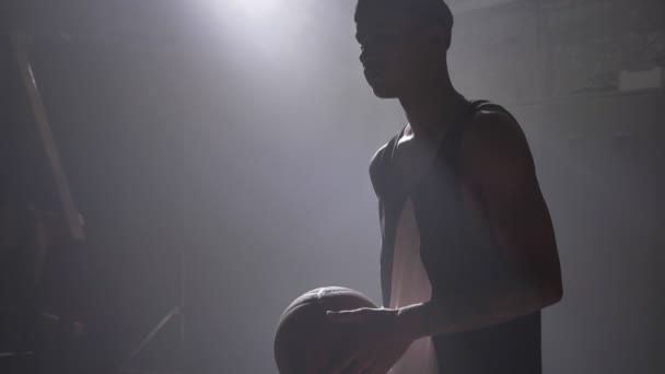 Afro-amerikanska basket spelare siluett förbereder sig för att kasta bollen, stående inomhus — Stockvideo