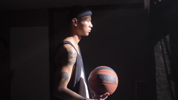 Handsome basketball player with tattoos playing with ball and waiting for game to start — Stock Video