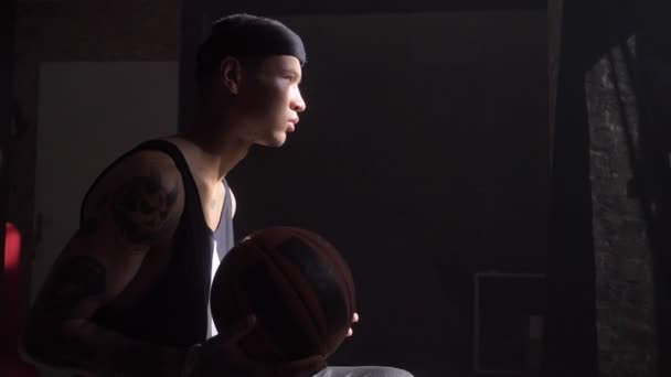 African basketball player sitting and playing with ball, waiting to go to playground for championnat — Stock Video