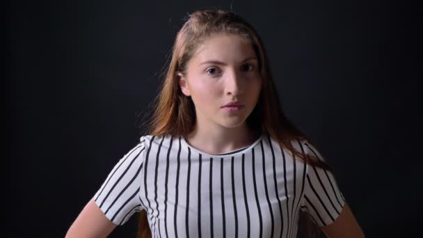 Besetzte junge Frau im gestreiften Hemd blickt in die Kamera und steht isoliert auf schwarzem Hintergrund — Stockvideo