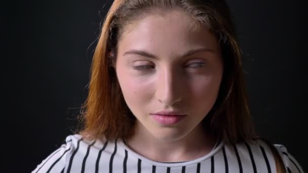 Porträt einer jungen Ingwerfrau, die in die Kamera blickt und lächelt, isoliert auf schwarzem Hintergrund — Stockvideo