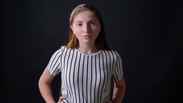 Angry young beautiful woman looking at camera with serious expression and standing isolated on black background — Stock Video