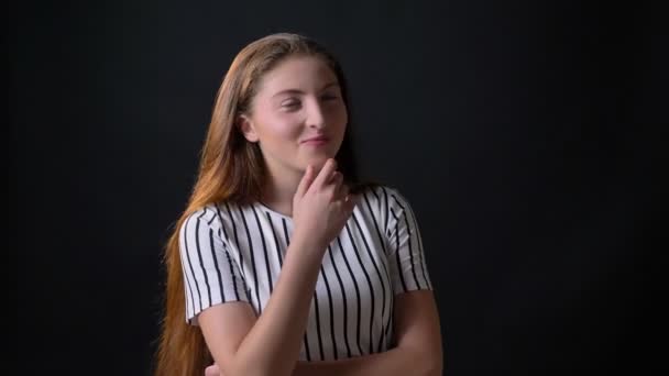 Happy young woman with ginger long hair smiling at camera, standing isolated on black background, laughing — Stock Video