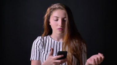 Söz konusu genç güzel kadın Kızıl saçlı siyah arka plan üzerine izole telefonda yazmaya konsantre