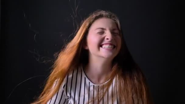 Jovem mulher bonita sorrindo e rindo, vento soprando seu longo cabelo de gengibre, alegre e feliz, fundo preto — Vídeo de Stock