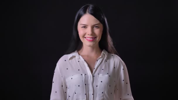 Schöne glückliche junge brünette Frau lächelt in die Kamera, isoliert auf schwarzem Hintergrund — Stockvideo