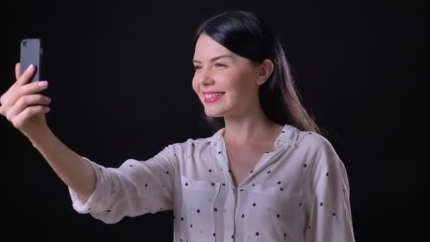 Vrij gelukkig jongedame video praatje en opdagen duimen, glimlachend en praten, geïsoleerd op zwarte achtergrond — Stockvideo